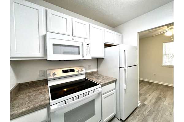 A kitchen with white cabinets and appliances.